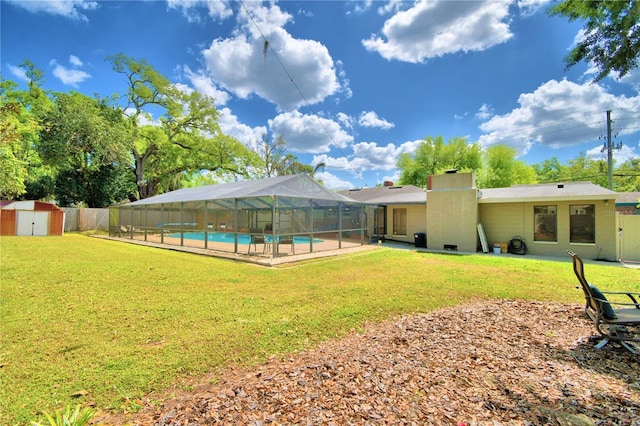 rear view of property featuring a lanai, a fenced in pool, a shed, and a lawn