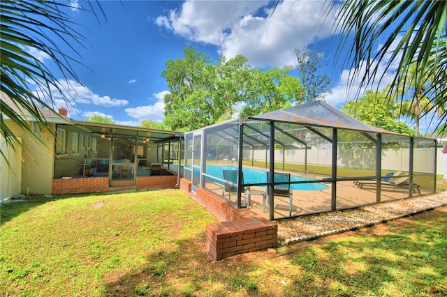 view of pool with a yard, glass enclosure, and a patio area