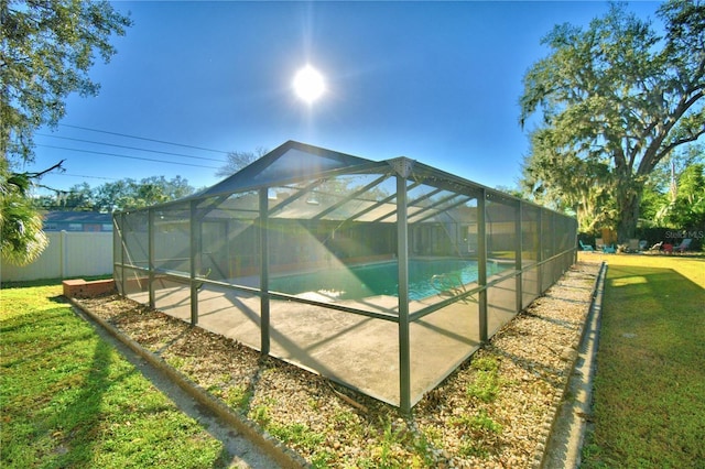 view of swimming pool featuring a yard and glass enclosure