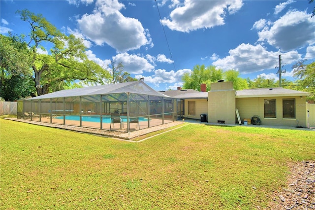 rear view of house with a fenced in pool, a lanai, and a lawn