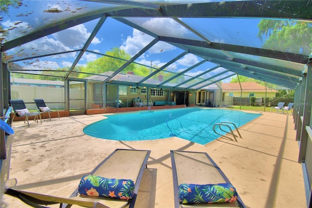 view of swimming pool with glass enclosure and a patio