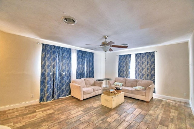 living room with ceiling fan and a textured ceiling