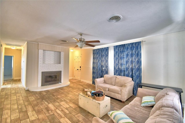 living room with ceiling fan and a fireplace