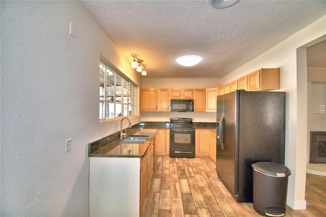 kitchen featuring light brown cabinetry, sink, a textured ceiling, light hardwood / wood-style flooring, and black appliances