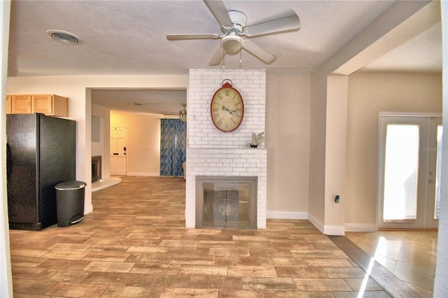 unfurnished living room featuring ceiling fan, a textured ceiling, a fireplace, and light hardwood / wood-style flooring