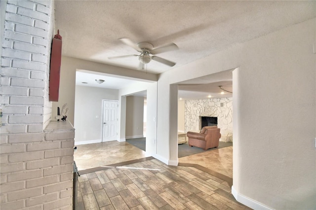 interior space featuring a textured ceiling, a fireplace, and ceiling fan