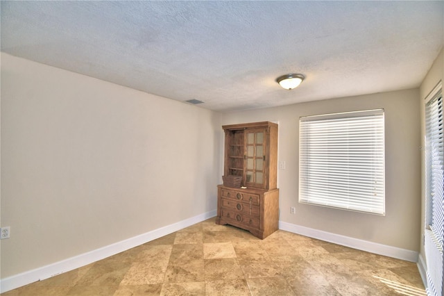 empty room with plenty of natural light and a textured ceiling