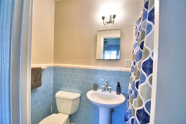 bathroom with toilet, curtained shower, sink, and tile walls