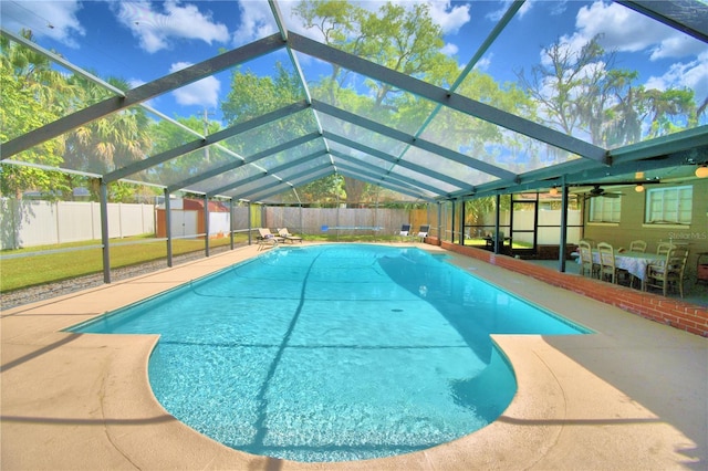 view of pool with a shed, a patio area, and glass enclosure