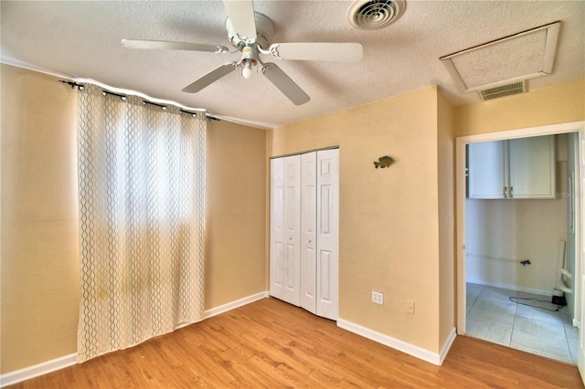 unfurnished bedroom with a textured ceiling, a closet, ceiling fan, and light wood-type flooring