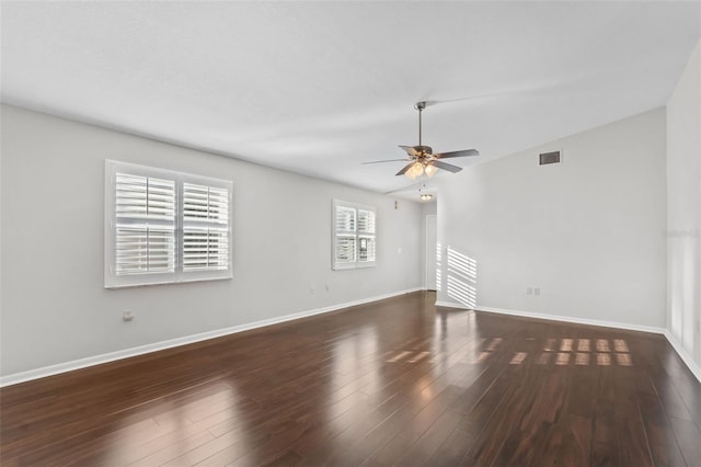 spare room featuring visible vents, a ceiling fan, dark wood finished floors, and baseboards