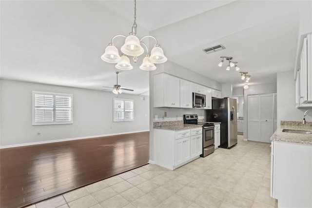 kitchen featuring appliances with stainless steel finishes, white cabinets, ceiling fan with notable chandelier, and a sink