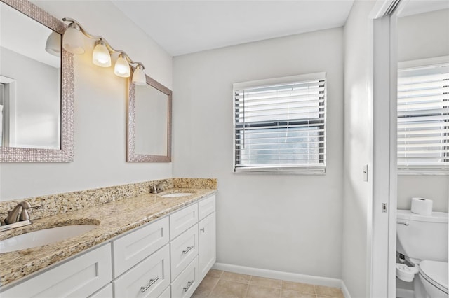 full bathroom featuring baseboards, toilet, double vanity, and a sink