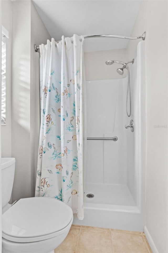 bathroom featuring toilet, a stall shower, and tile patterned floors