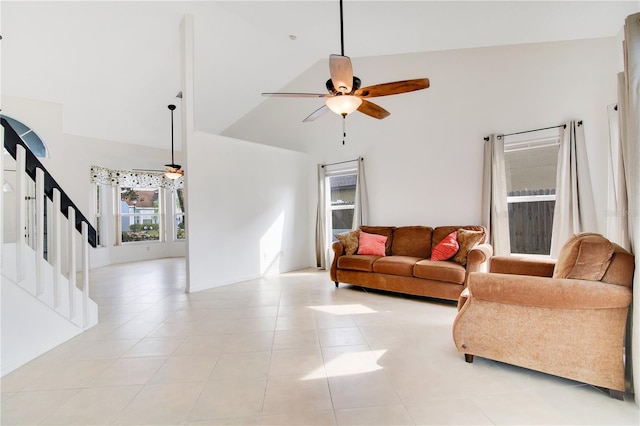 tiled living room with ceiling fan and high vaulted ceiling