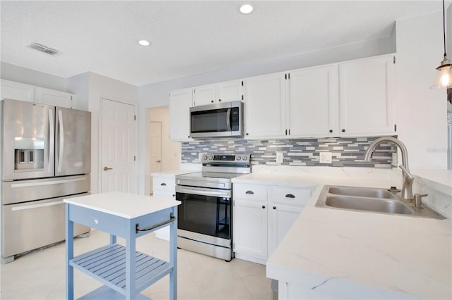 kitchen with appliances with stainless steel finishes, white cabinets, sink, and hanging light fixtures