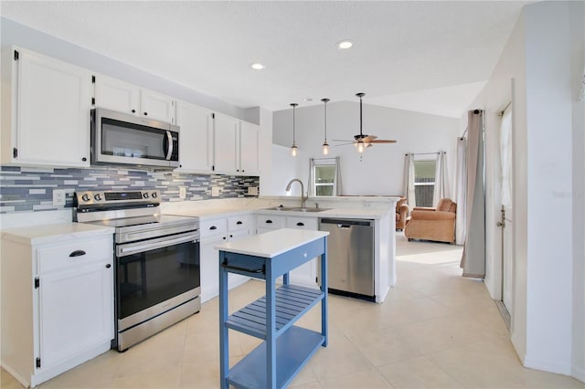 kitchen with lofted ceiling, kitchen peninsula, hanging light fixtures, sink, and appliances with stainless steel finishes