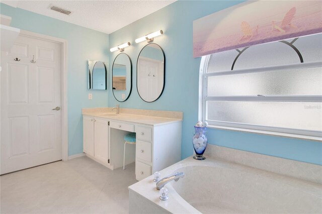 bathroom with vanity, a tub to relax in, and a textured ceiling