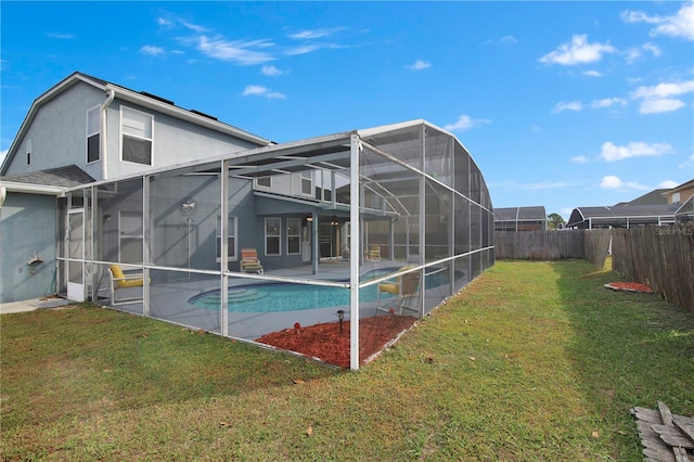 back of property with a lawn, glass enclosure, a patio area, and a fenced in pool