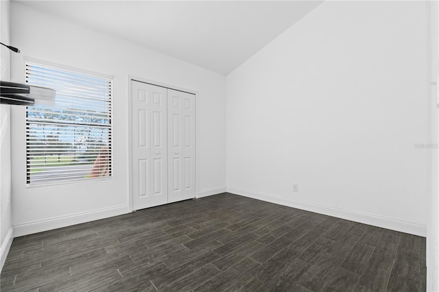 unfurnished bedroom featuring dark wood-type flooring, vaulted ceiling, and a closet