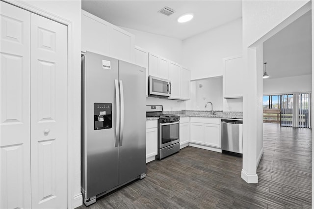 kitchen with dark hardwood / wood-style flooring, appliances with stainless steel finishes, white cabinetry, light stone countertops, and sink