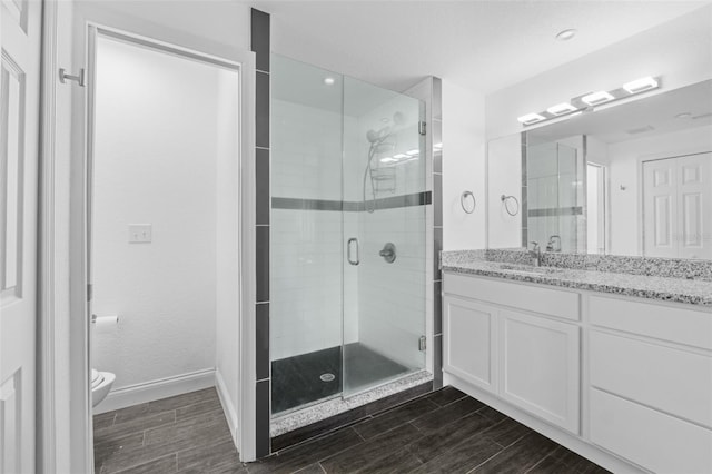 bathroom with vanity, a shower with shower door, and toilet