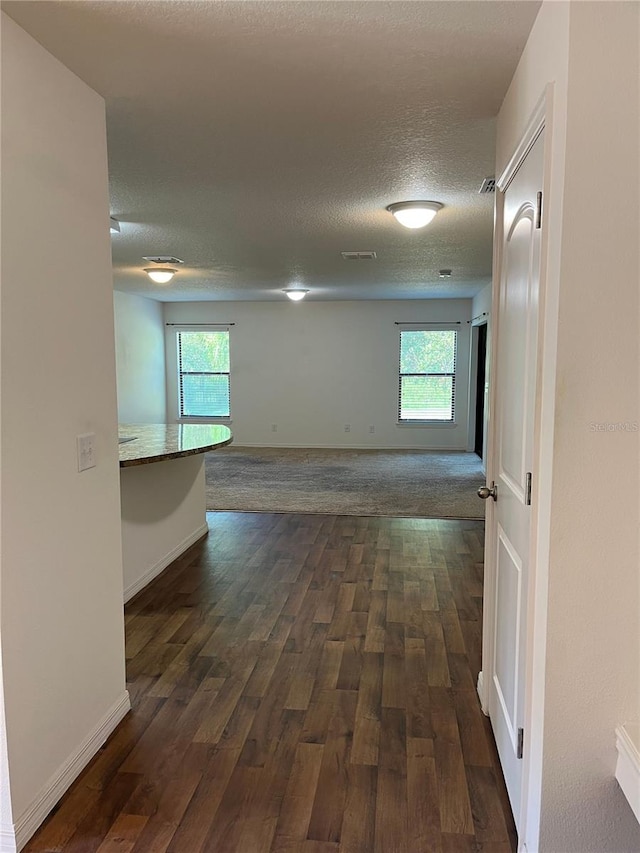 hall with a textured ceiling, plenty of natural light, and dark hardwood / wood-style flooring