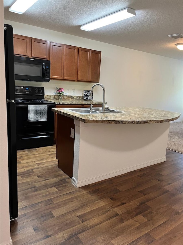 kitchen featuring a center island with sink, a textured ceiling, dark hardwood / wood-style floors, black appliances, and sink