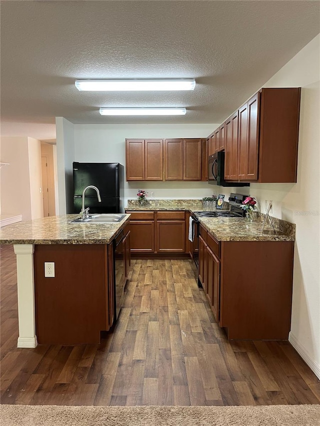 kitchen with dark wood-type flooring, black appliances, a textured ceiling, and sink