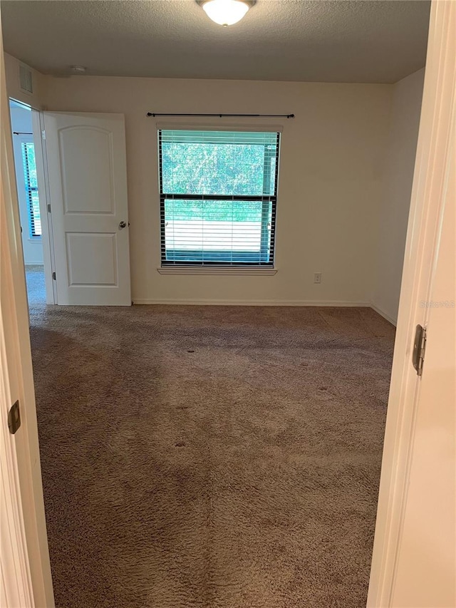 carpeted spare room featuring a textured ceiling