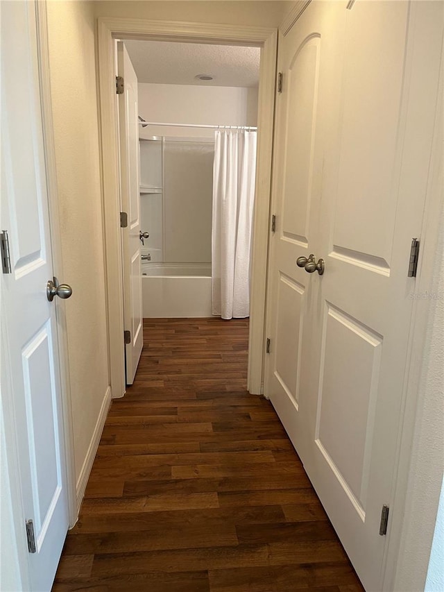 corridor with a textured ceiling and dark hardwood / wood-style floors