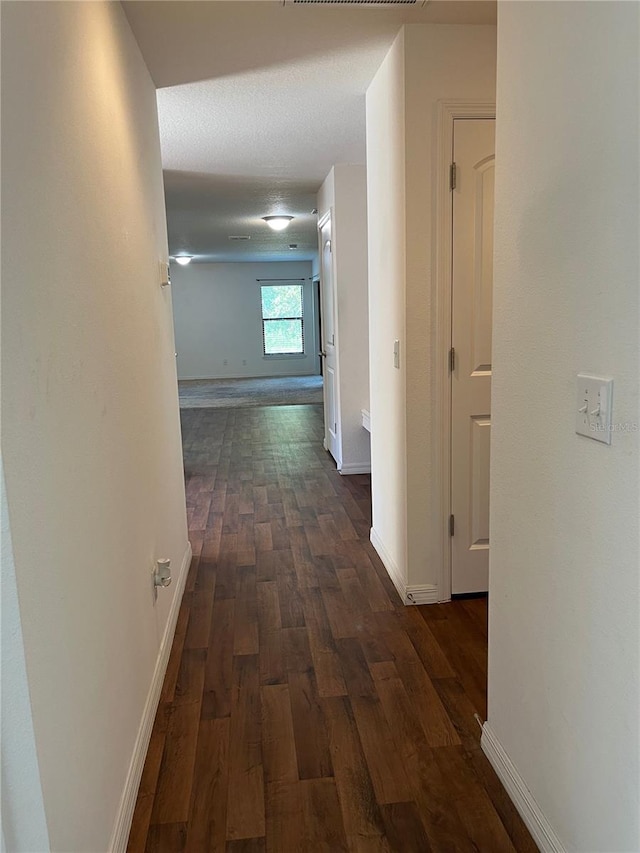 hall with a textured ceiling and dark hardwood / wood-style flooring