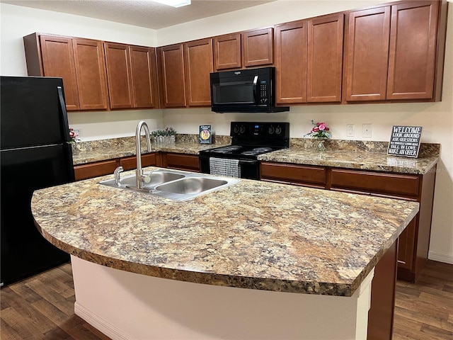 kitchen with sink, black appliances, dark hardwood / wood-style flooring, and an island with sink