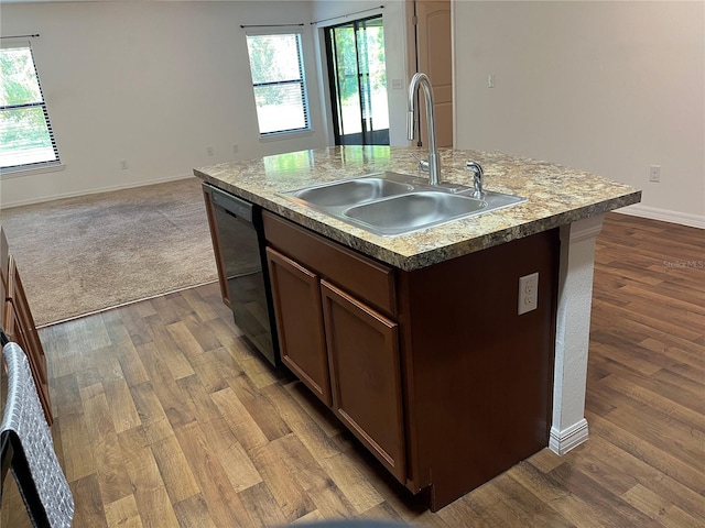 kitchen with hardwood / wood-style floors, black dishwasher, sink, and an island with sink