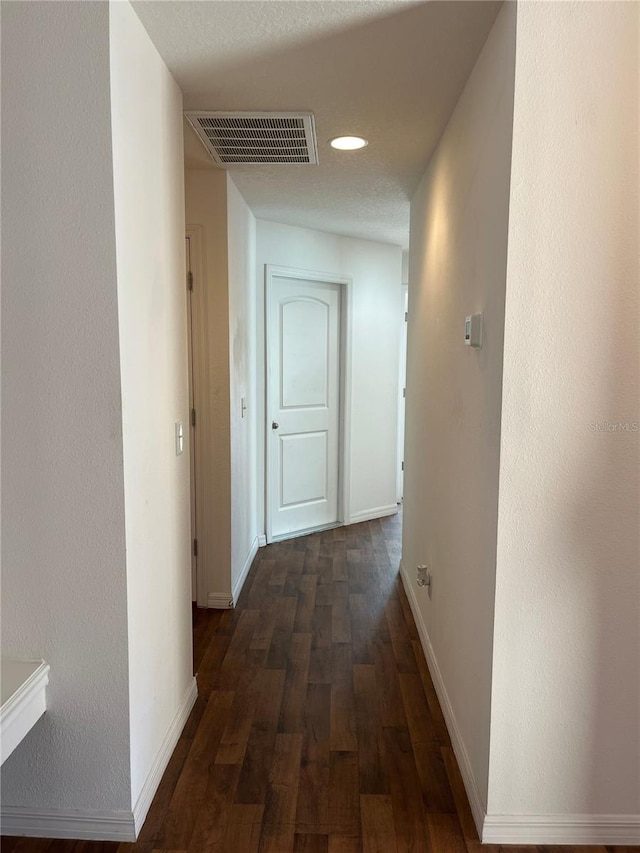 hall featuring baseboards, visible vents, dark wood-type flooring, and recessed lighting