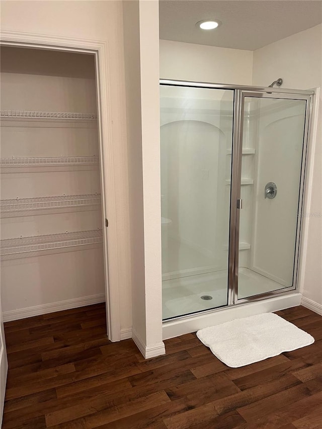 bathroom featuring a stall shower, baseboards, and wood finished floors