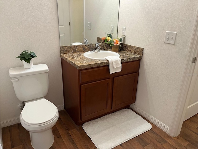 bathroom with toilet, baseboards, wood finished floors, and vanity