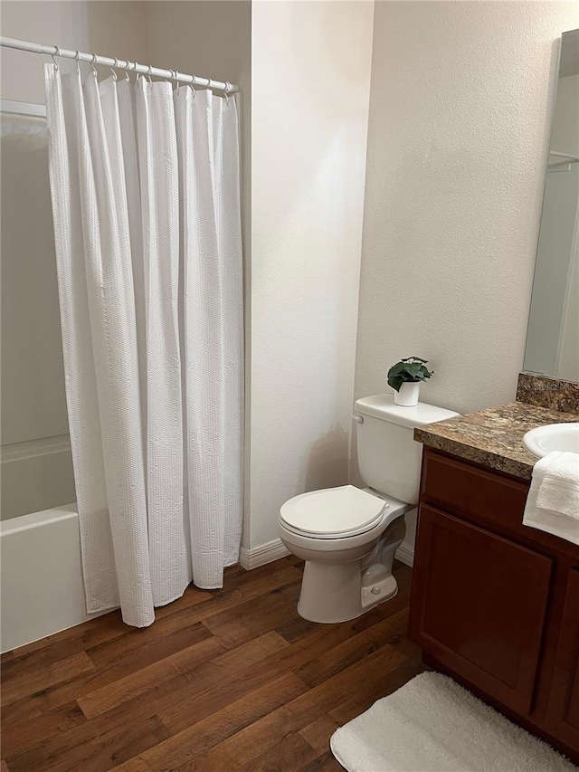 full bath with toilet, shower / tub combo, wood finished floors, and vanity