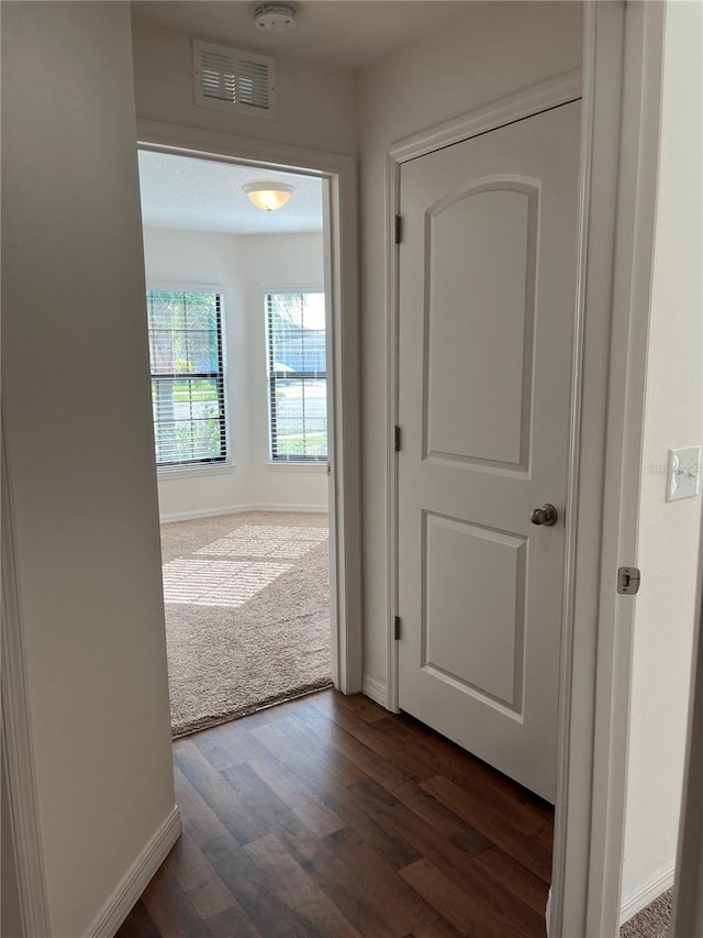 corridor featuring visible vents, dark wood finished floors, and baseboards