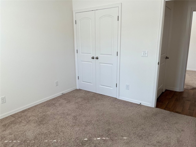 unfurnished bedroom with carpet floors, a closet, and baseboards