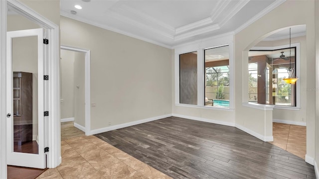 unfurnished room with crown molding, a raised ceiling, and wood-type flooring