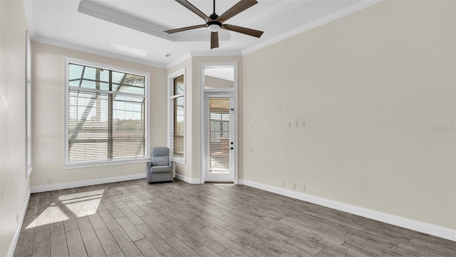 unfurnished room featuring wood-type flooring, ornamental molding, a raised ceiling, and ceiling fan