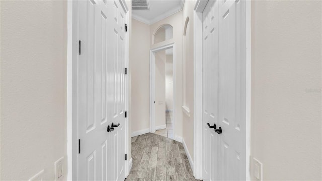 hallway with crown molding and light wood-type flooring