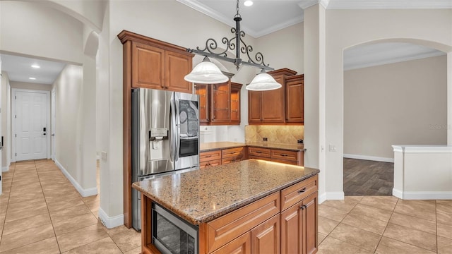 kitchen with pendant lighting, appliances with stainless steel finishes, light stone counters, ornamental molding, and light tile patterned flooring