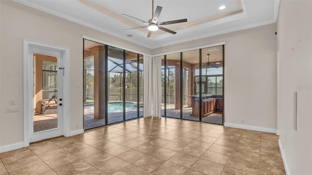 empty room featuring ceiling fan, ornamental molding, a tray ceiling, and light tile patterned floors