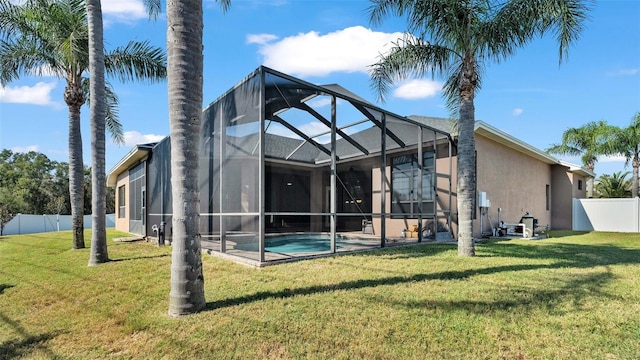 back of property with a fenced in pool, a lawn, and glass enclosure