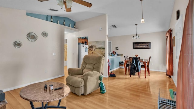 living area with vaulted ceiling, wood-type flooring, and ceiling fan with notable chandelier