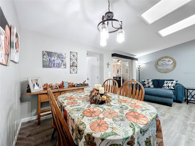 dining area featuring wood-type flooring and an inviting chandelier