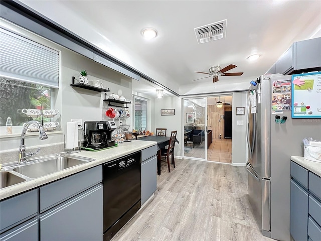 kitchen featuring black dishwasher, light hardwood / wood-style flooring, stainless steel fridge, sink, and ceiling fan