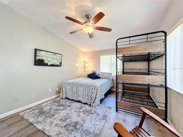 bedroom featuring lofted ceiling, a textured ceiling, hardwood / wood-style flooring, and ceiling fan